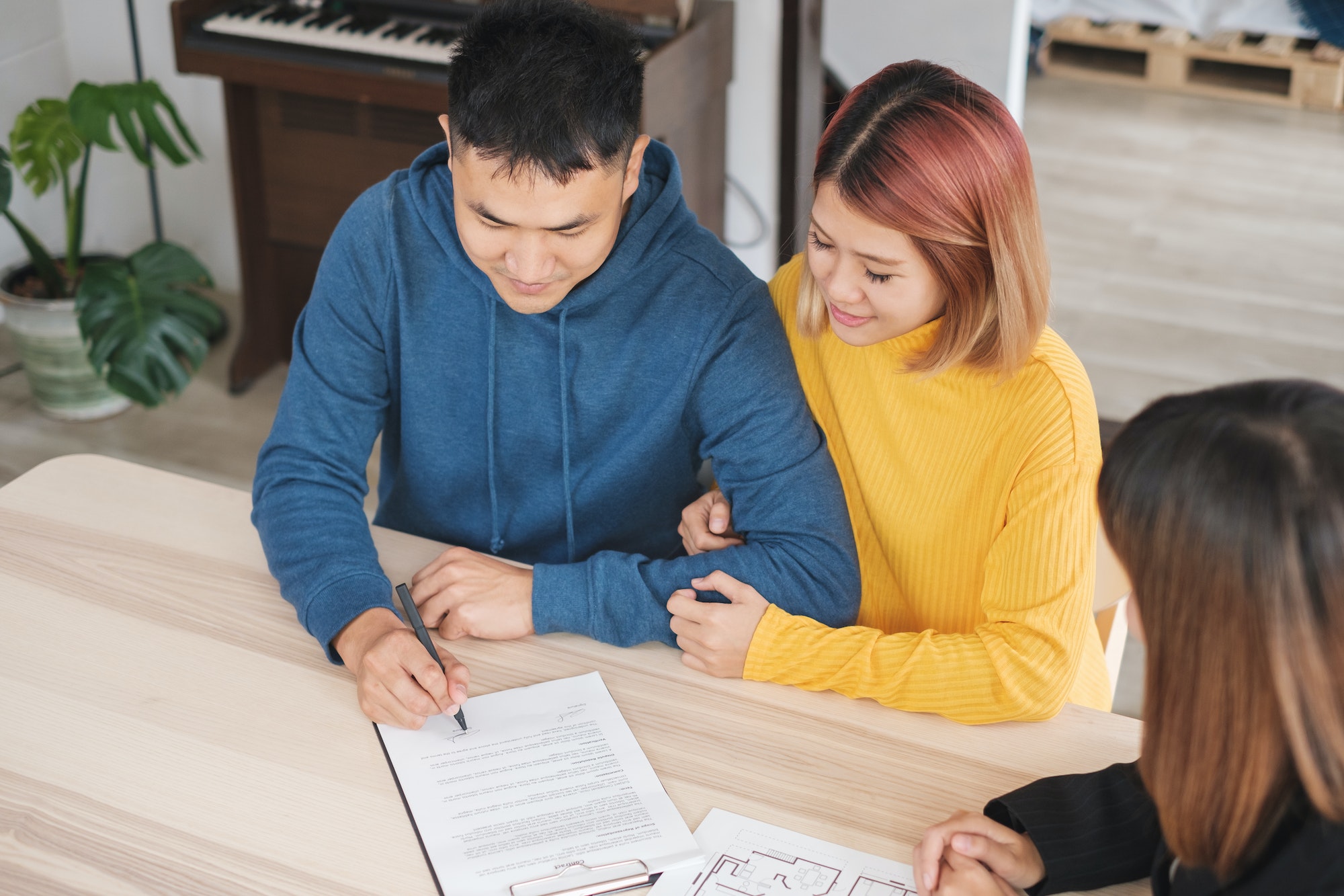 Asian happy couple sign contract buying new home with realtor agent